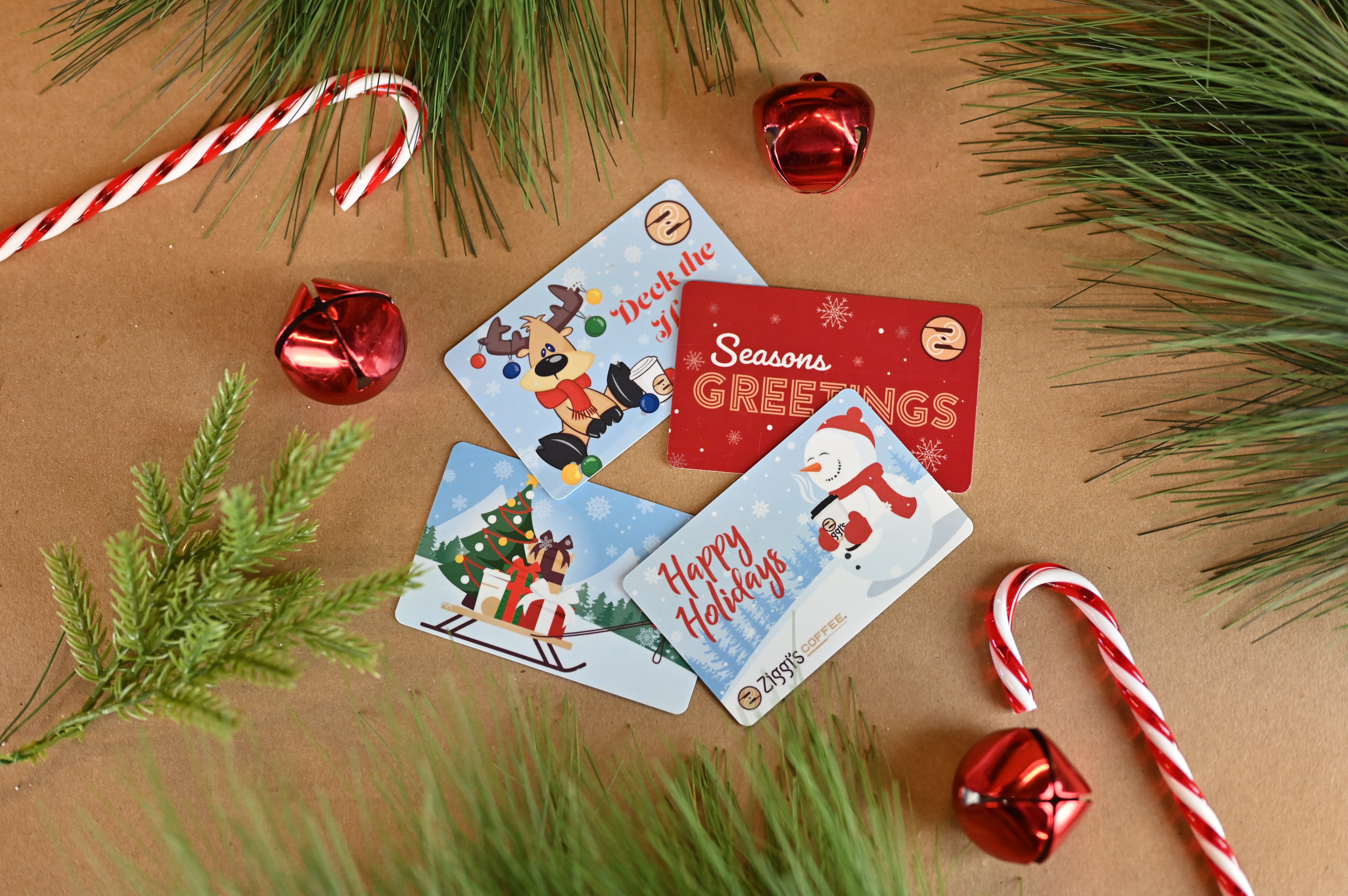 four holiday gift cards laid on top of one another with candy canes and holiday decors around it 