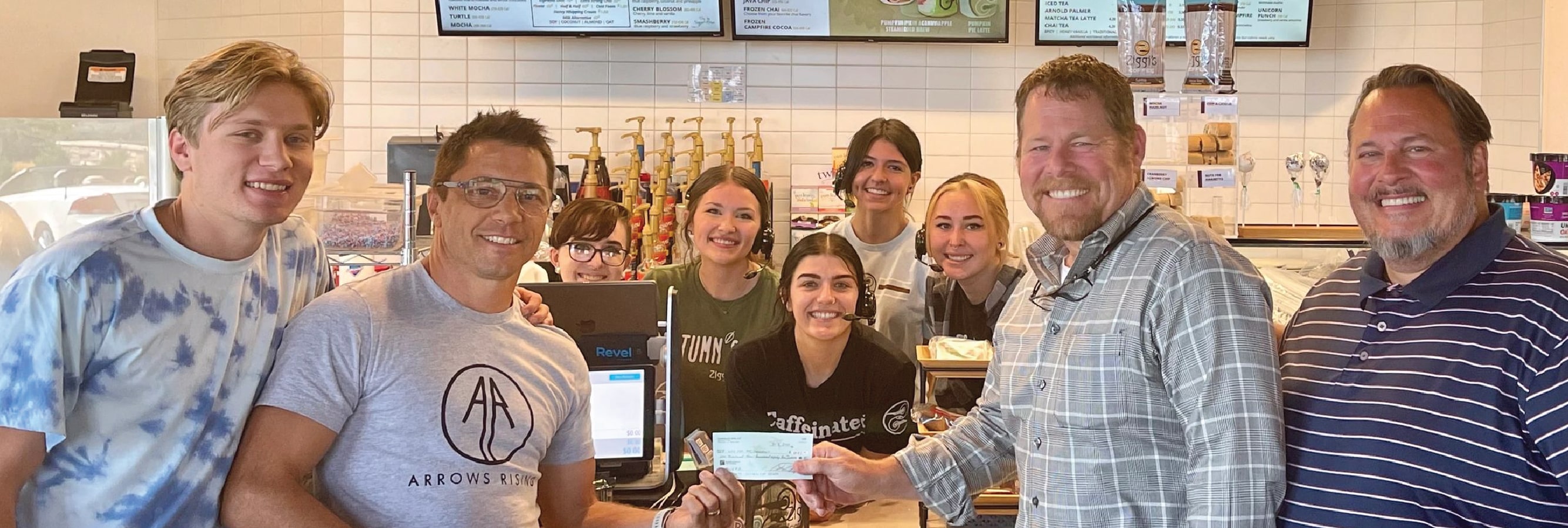 group of people in a cafe presenting a donation check